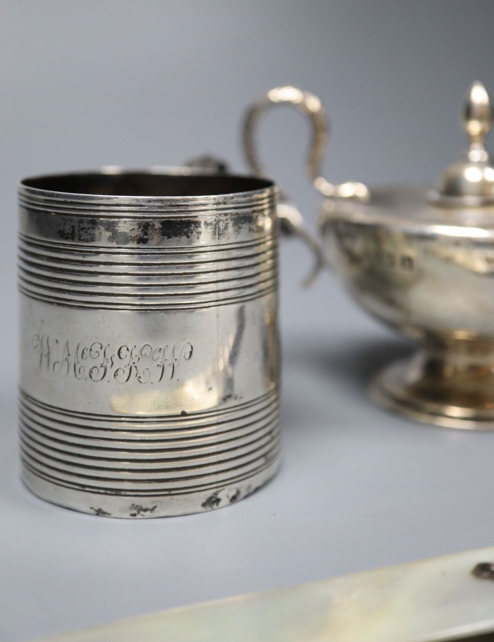 A George III reeded silver small mug, London, 1807, 6.3cm, an Edwardian Aladdins lamp perpetual lighter and a paper knife.